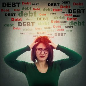 Anxious woman holding her head in both hands with the word ‘DEBT’ above her